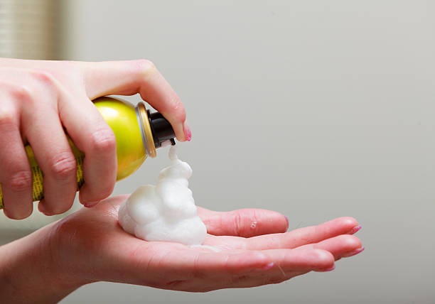 Close-up of hairdresser hairstylist female hand with hair mousse spray. Professional cosmetic in hairdressing beauty salon.