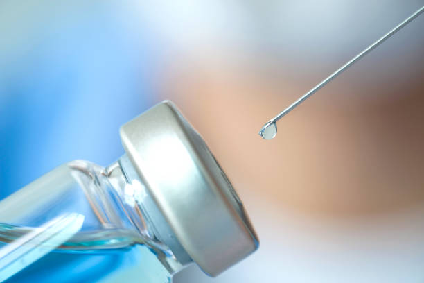 doctor's hand holds a syringe and a blue vaccine bottle at the hospital. Health and medical concepts
