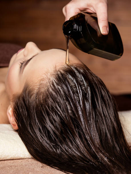 Cosmetologist pours balm for hair on the head of the woman. Spa treatments. Beauty treatment. Spa salon